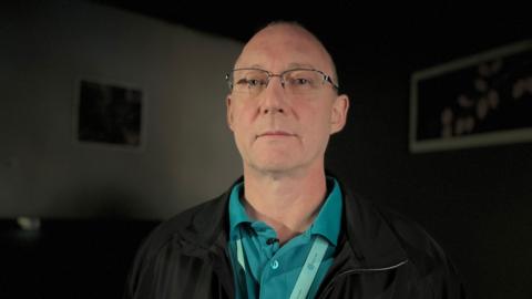 Man wearing an inspectors uniform in a dark damp room