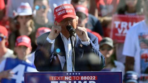 Trump at lectern with fists up in front of seated supporters