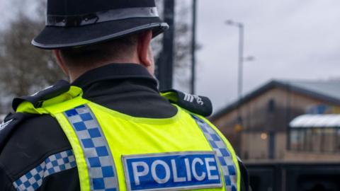 A stock image of a uniformed police officer pictured from behind.