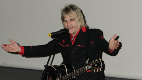 The Alarm singer Mike Peters on stage with a guitar around his neck