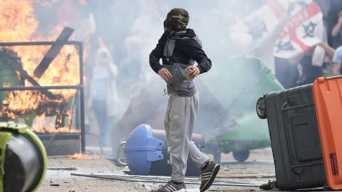 A man at a riot in Rotherham, with fire in the background