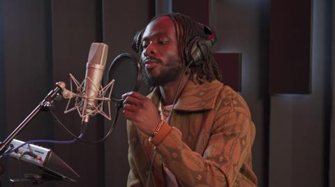 Fuse ODG pictured in the studio recording vocals into a microphone