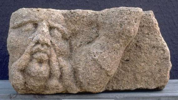 Grey stone sculpture of man's head and horse's hoof