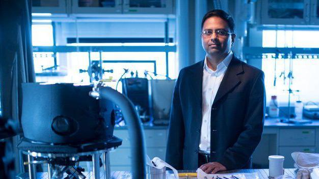 Prof Varanasi standing in a laboratory surrounded by lab equipment