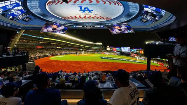 Baseball fans watch a giant LED screen showing Game 3 of the World Series between the Dodgers and the New York Yankees live in the Dome at Cosm Los Angeles