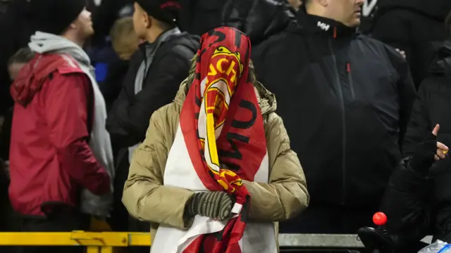 Man Utd fan with draped flag over their head