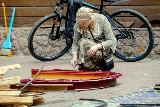 A woman cleans religious icons near a damaged church after a missile strike in Odesa