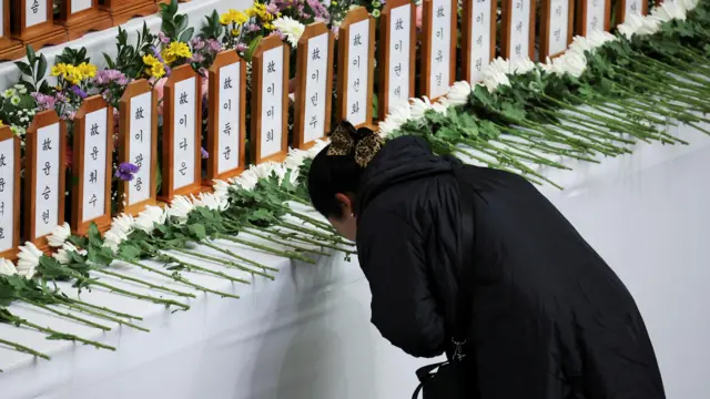 A woman prays at a memorial altar for the victims of the Jeju Air crash at Muan International Airport, at Muan Sports Park in Muan, South Korea