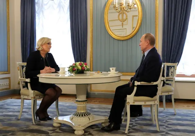 Marine Le Pen and Vladimir Putin sat around a table