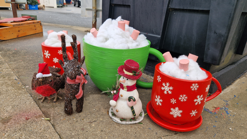 Two plant pots have been upcycled to become large hot chocolates, complete with cream and marshmallows on top.  A reindeer and a snowman sit at the side.