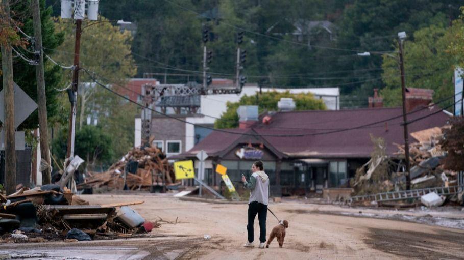 A woman and her dog walk around the Biltmore Village in the aftermath of Hurricane Helene in Asheville, North Carolina