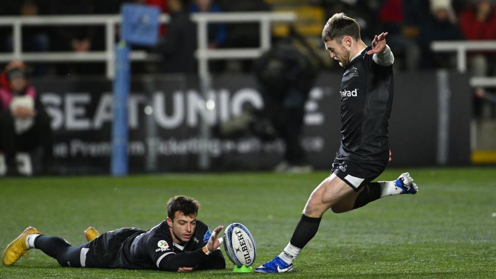 Adam Radwan lying down to help tee up the ball for Newcastle teammate Brett Conway during a conversion attempt.