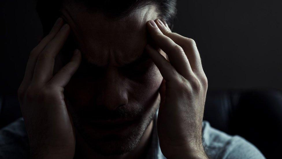 A man with his head in his hands (posed by model)