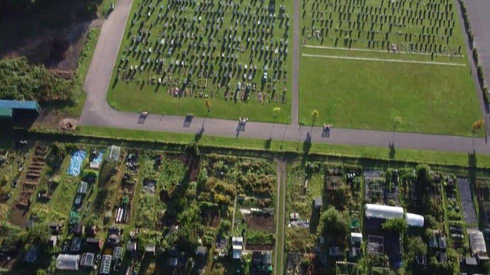 Allotments divided by a road with multiple graves on two regtangular grassed areas