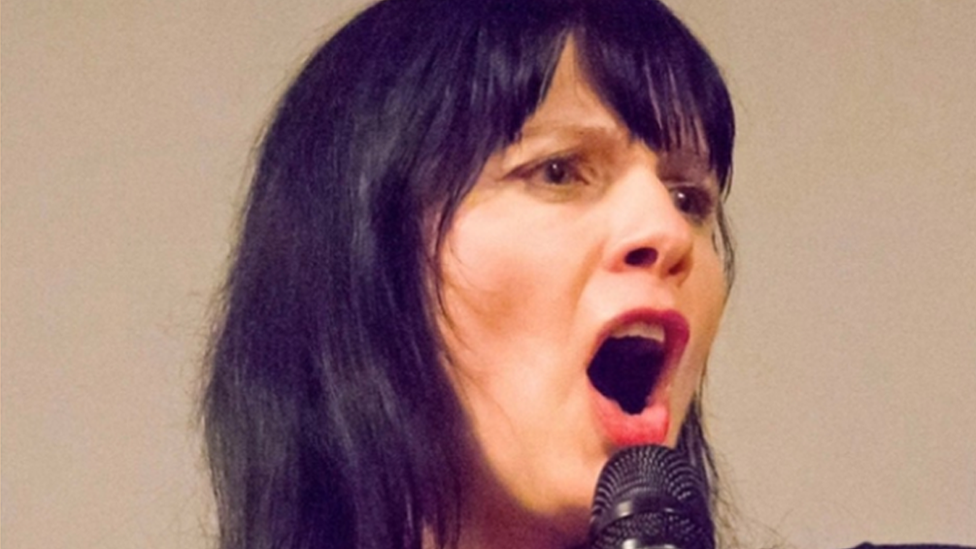 Comedian Lizzy Lenco on stage talking into a microphone