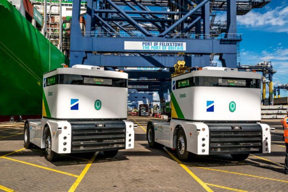 Autonomous white trucks underneath blue metal towers at Felixstowe Port.