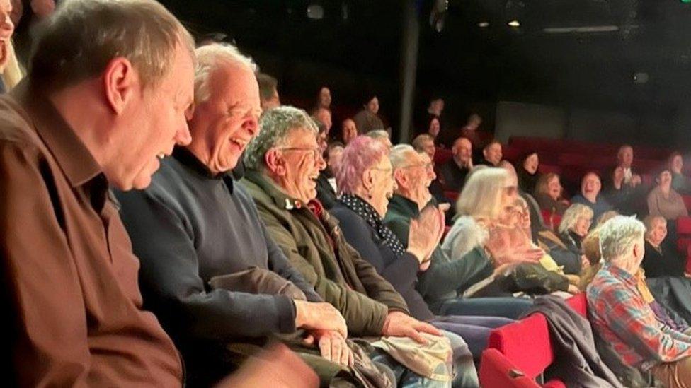 A crowd of people at the theatre laughing