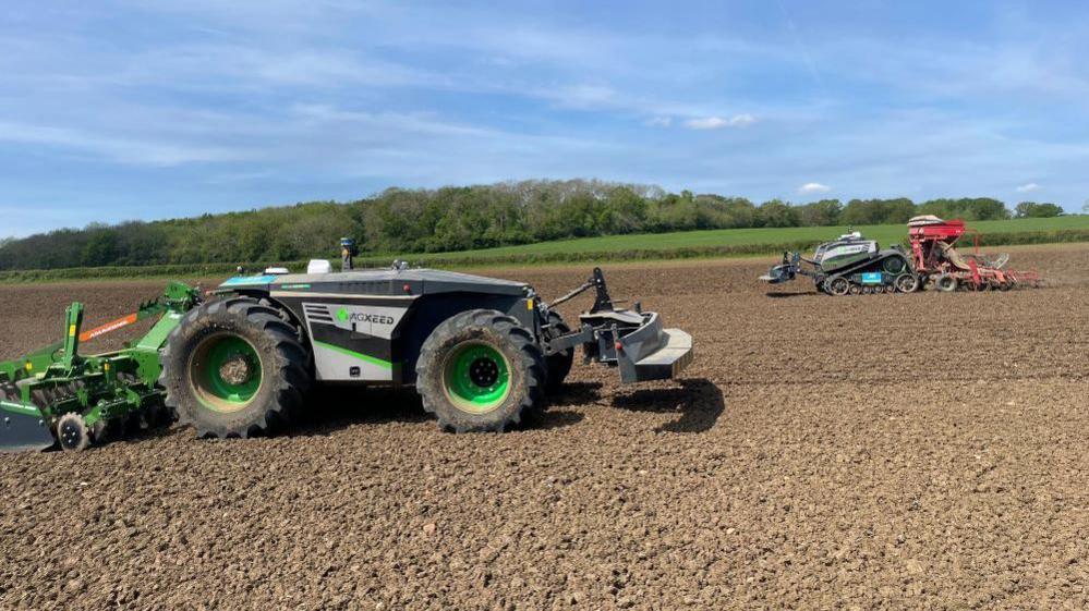 Two driverless tractors on farmland