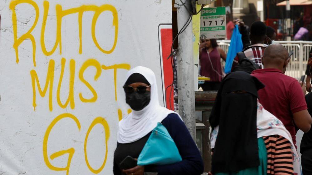 People walk next to a graffiti done by protesters who were against the imposition of tax hikes by the government, in Nairobi, Kenya, July 4, 2024