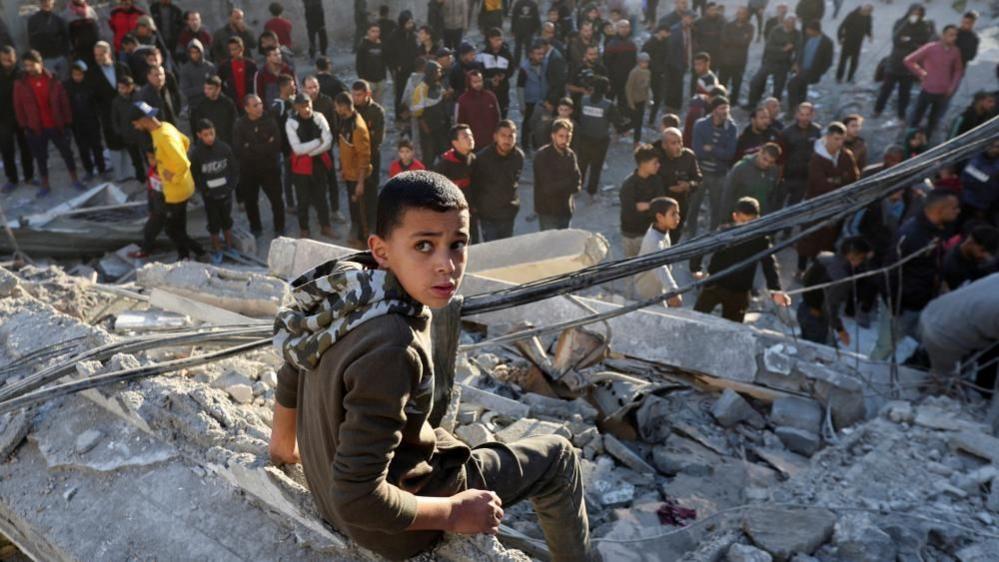 A Palestinian child sits at the site of an Israeli strike, amid the Israel-Hamas conflict, at the Nuseirat refugee camp in the central Gaza Strip, December 13, 2024.