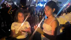 Dos niñas con velas en el chigualo.