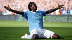 Emmanuel Adebayor célèbre un but pour Manchester City en s'agenouillant et en étirant ses bras devant les supporters d'Arsenal en 2009.