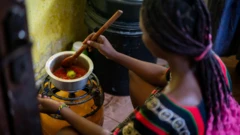 Mulher agachada cozinhando em cima de botijão