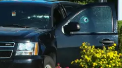 Image shows a bullet-riddled vehicle near the shooting site