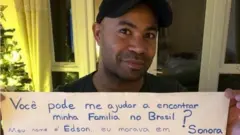 Edson segurando cartaz com informações sobre seus pais e sua adoção