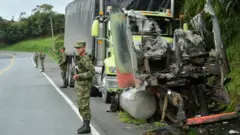 Soldados perto de caminhão queimado parado no acostamento de uma estrada