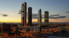 Foto colorida mostra prédios de Madri durante o por do sol