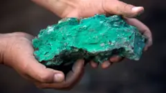 A turquois cobalt rock held in a pair of hands