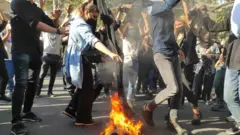 A woman burns her headscarf on a bonfire at a protest in Tehran, Iran (1 October 2022)