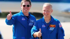 Bob Behnken e Doug Hurley, de jalecos da Nasa, pousam para foto sorrindo