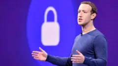 Mark Zuckerberg gestures with arms open in front of a padlock symbol on stage during a privacy speech