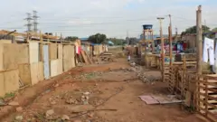 Rua de chão batido e casas improvisadas com madeira