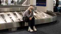 A traveler sits in baggage claim at LaGuardia Airport in New York, on December 24, 2021