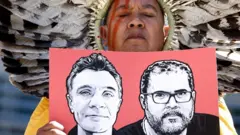 Membro da Articulação dos Povos Indígenas do Brasil (Apib) segura uma imagem do jornalista britânico Dom Phillips e do indigenista brasileiro Bruno Pereira