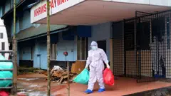 Um oficial de saúde está do lado de fora da enfermaria do Kozhikode Medical College Hospita