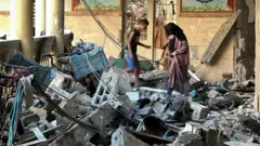 People inspect damage at the school building, 10 August 2024