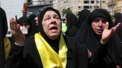 Uma mulher de hijab preto e pano amarelo chora em funeral