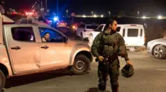 Israeli soldier stands in middle of road as cars are parked up around him after drone attack in Binyamina, Israel on 13 October