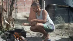 Jamile Carvalho cozinhando em um fogão improvisado