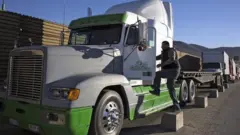 Un hombre subiendo a un camión de carga en la frontera entre México y EE.UU.