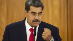 O presidente da Venezuela, Nicolás Maduro. Ele usa terno escuro, camisa branca e gravata vermelha. No pulso, usa um relógio prateado