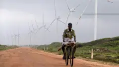 Um homem passa de bicicleta por um parque eólico no Sri Lanka, país que está se voltando cada vez mais para as energias renováveis ​​após uma crise econômica causada em parte pelos altos custos de energia