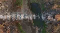 Foto feita por um drone mostra uma ponte queimada sobre uma pequena área com água com o entorno todo seco