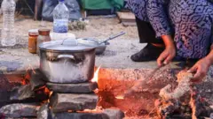 Refugiada com cozinha improvisada, na Grécia