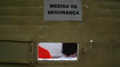 Foto de uma porta de prisão com placa "Medida de segurança"