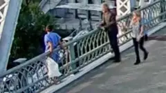 A low quality grab shows Jon Bon Jovi speaking to the woman on the bride, with a passer by in frame